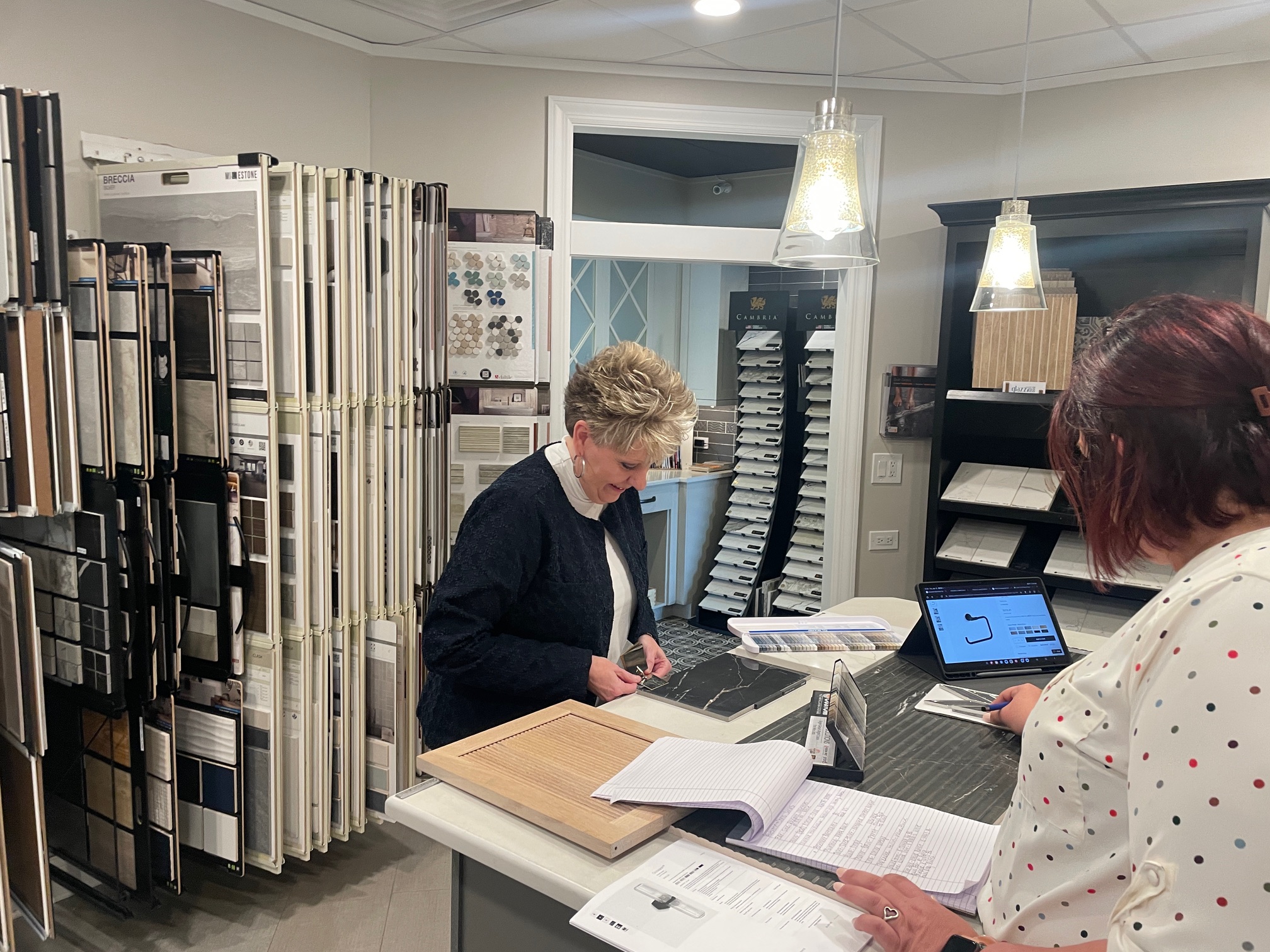 Designer and Planner Working Together Women working with blueprints for home remodel while another woman assists her.