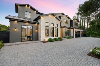 Modern luxury home exterior with a spacious driveway and well-lit facade at sunset.