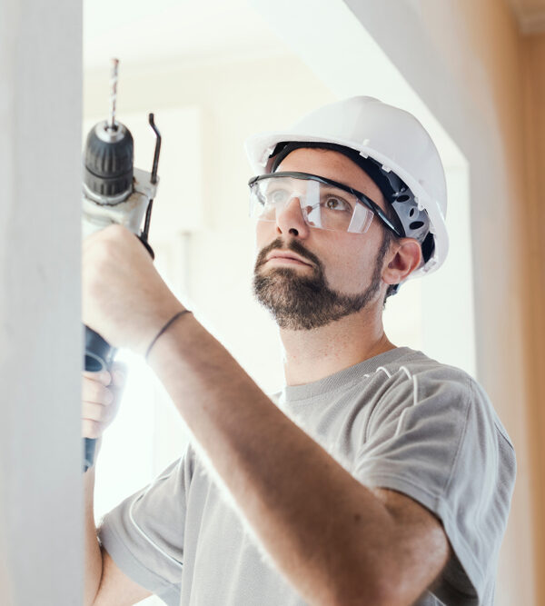 Professional,Construction,Worker,Using,A,Drill,,He,Is,Wearing,A Professional construction worker using a drill, he is wearing a safety helmet and goggles